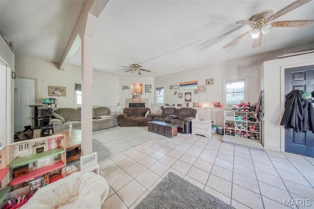 110 S Oak St, Rolla, MO 65401 - living room featuring ceiling fan, a fireplace, light tile patterned floors, and a textured ceiling