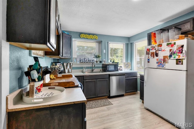 503 Emerson St, Kennett, MO 63857 - kitchen with freestanding refrigerator, stainless steel dishwasher, black microwave, light countertops, and a textured ceiling
