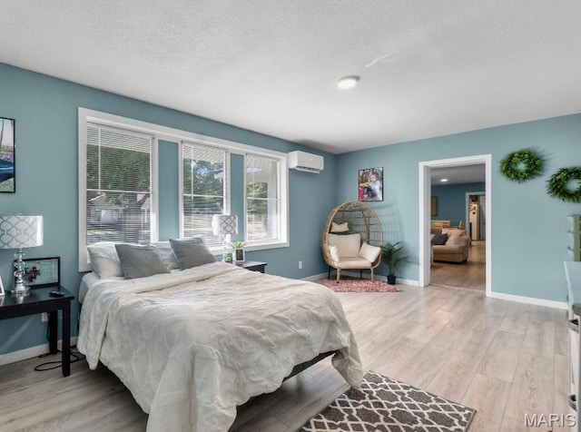 503 Emerson St, Kennett, MO 63857 - bedroom featuring light wood-style flooring, a wall unit AC, and a textured ceiling