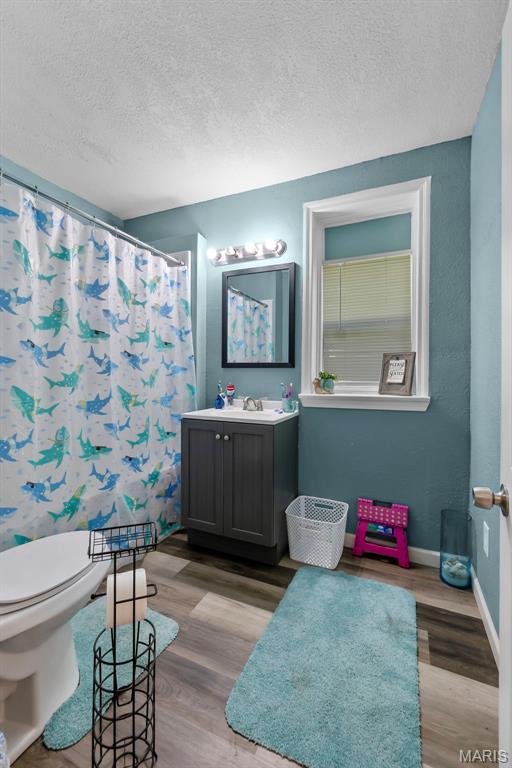 503 Emerson St, Kennett, MO 63857 - bathroom with vanity, wood finished floors, a textured ceiling, and curtained shower