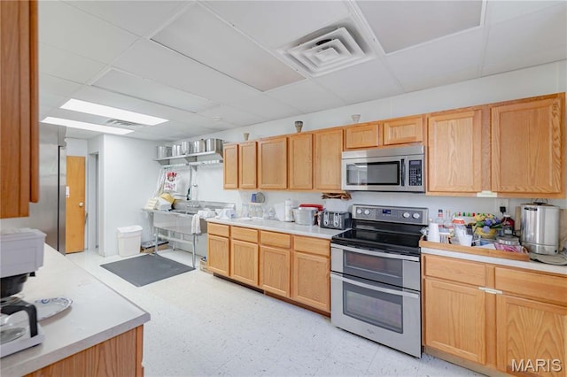 4869 Scottsdale Rd, House Springs, MO 63051 - kitchen featuring appliances with stainless steel finishes, light countertops, light brown cabinetry, light flooring, and a drop ceiling