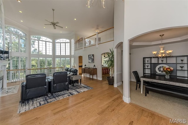 2314 Longest Dr, Wentzville, MO 63385 - living area with a chandelier, ceiling fan, arched walkways, a towering ceiling, and crown molding