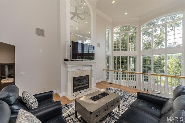 2314 Longest Dr, Wentzville, MO 63385 - living area featuring a towering ceiling, a tile fireplace, plenty of natural light, crown molding, and wood finished floors