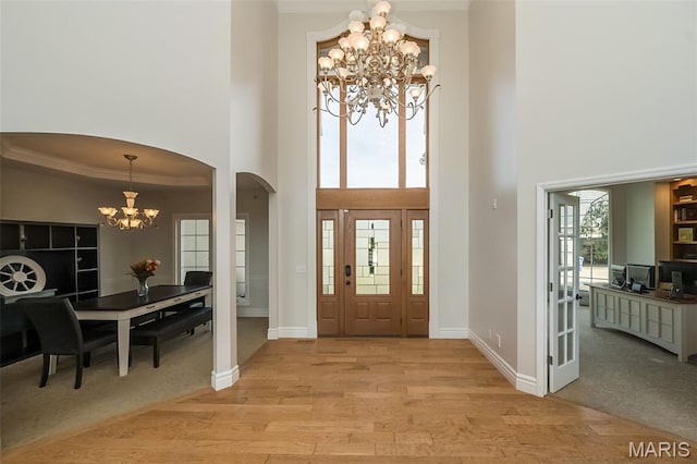 2314 Longest Dr, Wentzville, MO 63385 - entrance foyer featuring a chandelier, a towering ceiling, arched walkways, light wood-type flooring, and ornamental molding