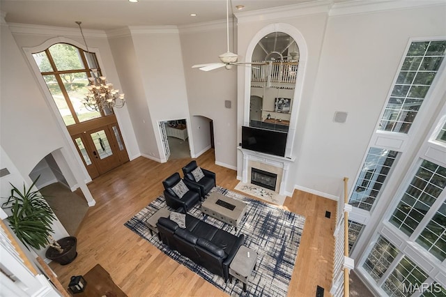 2314 Longest Dr, Wentzville, MO 63385 - living room featuring arched walkways, wood finished floors, a ceiling fan, ornamental molding, and a fireplace with flush hearth