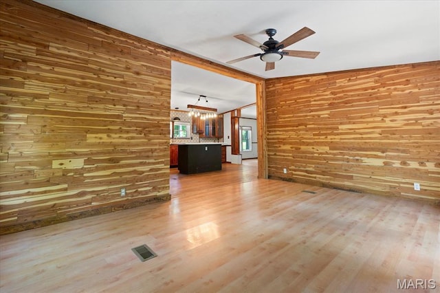 434 Cool Springs Ln, Wright City, MO 63390 - unfurnished living room featuring wood walls, a chandelier, ceiling fan, and light wood finished floors