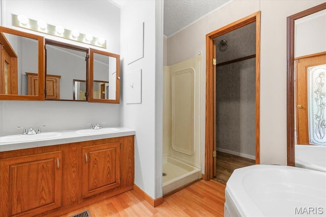 434 Cool Springs Ln, Wright City, MO 63390 - bathroom featuring wood finished floors, a stall shower, double vanity, a bath, and a textured ceiling