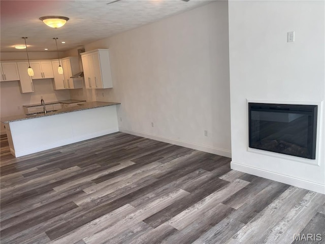 314 Captains Ct, Grafton, IL 62037 - kitchen with dark wood-type flooring, dark stone counters, white cabinetry, a glass covered fireplace, and wall chimney exhaust hood