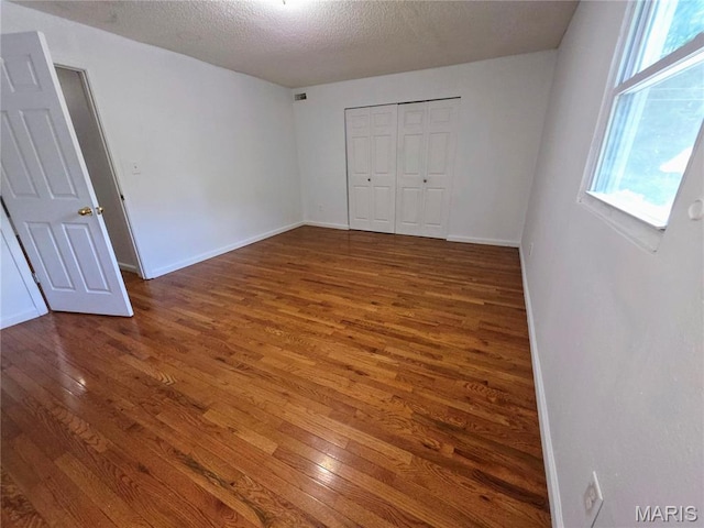 123 W Wickliffe Ave, Collinsville, IL 62234 - unfurnished bedroom with wood finished floors, multiple windows, a closet, and a textured ceiling