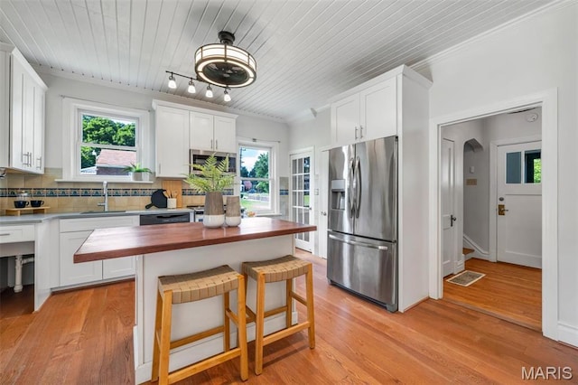 2733 Hermitage Ave, Saint Louis, MO 63143 - kitchen with appliances with stainless steel finishes, butcher block counters, white cabinets, decorative backsplash, and healthy amount of natural light