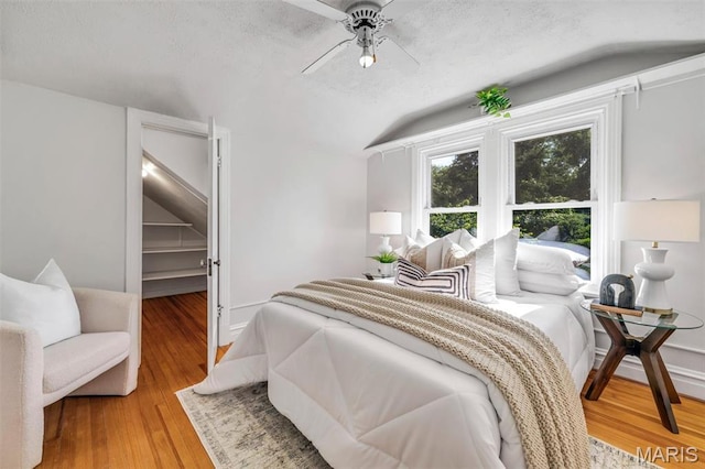 2733 Hermitage Ave, Saint Louis, MO 63143 - bedroom featuring vaulted ceiling, light wood finished floors, a textured ceiling, a ceiling fan, and a walk in closet