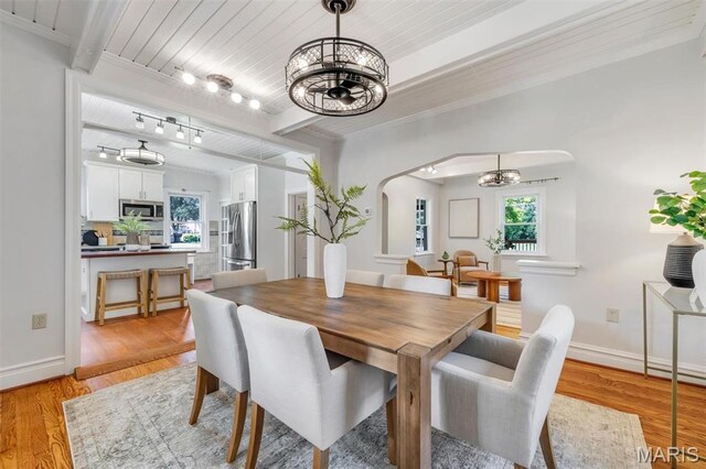 2733 Hermitage Ave, Saint Louis, MO 63143 - dining room with a chandelier, arched walkways, healthy amount of natural light, light wood-style flooring, and a wood ceiling with exposed beams