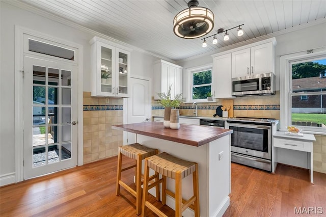 2733 Hermitage Ave, Saint Louis, MO 63143 - kitchen with stainless steel appliances, butcher block countertops, white cabinets, crown molding, and light wood-type flooring