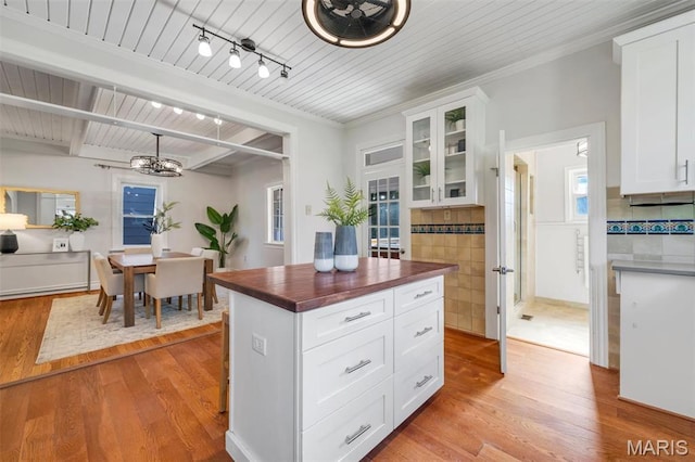 2733 Hermitage Ave, Saint Louis, MO 63143 - kitchen featuring a chandelier, light wood-style flooring, butcher block countertops, glass insert cabinets, and a wood ceiling with exposed beams