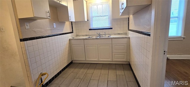 6128 Bircher St, Saint Louis, MO 63120 - kitchen featuring white cabinets, light wood-style floors, tile walls, and light countertops