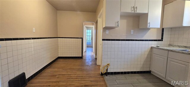 6128 Bircher St, Saint Louis, MO 63120 - kitchen featuring tile walls, white cabinets, dark wood-type flooring, and a wainscoted wall