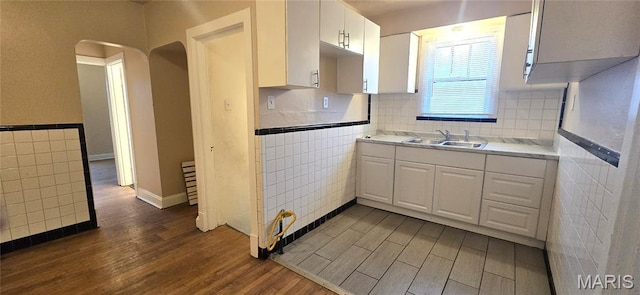 6128 Bircher St, Saint Louis, MO 63120 - kitchen featuring tile walls, dark wood-style flooring, arched walkways, white cabinets, and light countertops