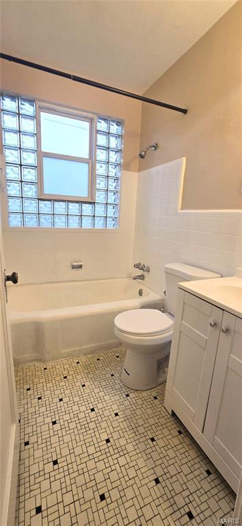 6128 Bircher St, Saint Louis, MO 63120 - full bath featuring vanity, tile walls, shower / tub combination, tile patterned floors, and wainscoting