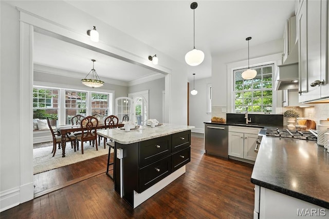 6336 Pershing Ave, University City, MO 63130 - kitchen featuring stainless steel dishwasher, backsplash, dark wood-type flooring, a kitchen bar, and decorative light fixtures