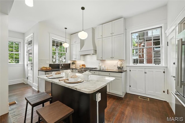 6336 Pershing Ave, University City, MO 63130 - kitchen featuring custom range hood, dark wood-type flooring, and backsplash