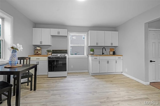 2162 State St, Granite City, IL 62040 - kitchen with gas range gas stove, light wood-style floors, white cabinetry, and butcher block counters