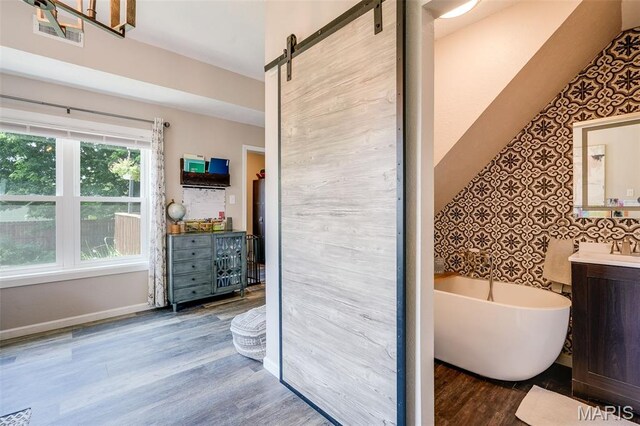 116 N Washington St, Troy, IL 62294 - full bath with vanity, a freestanding tub, wood finished floors, and wallpapered walls