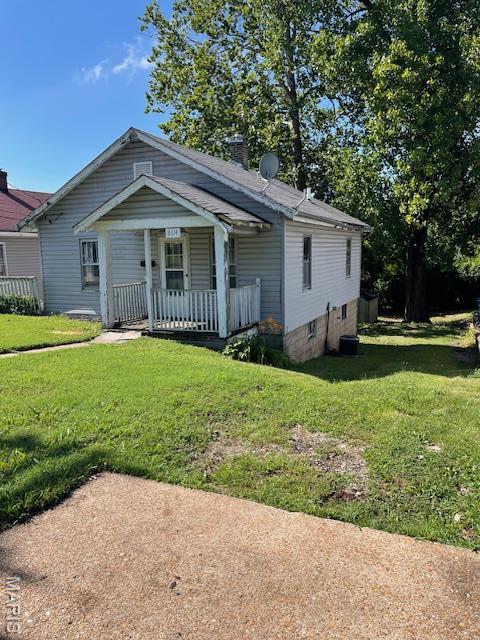 8614 Hume Ave, St John, MO 63114 - view of front of property with covered porch, a front yard, and a chimney