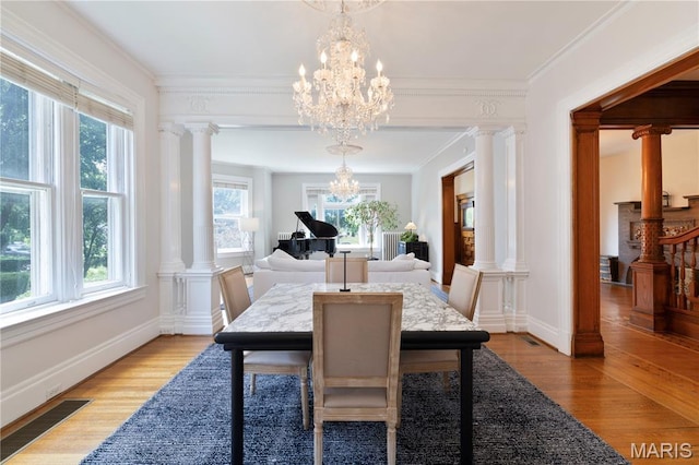 4365 Forest Park Ave, Saint Louis, MO 63108 - dining room featuring light wood finished floors, crown molding, a chandelier, and decorative columns