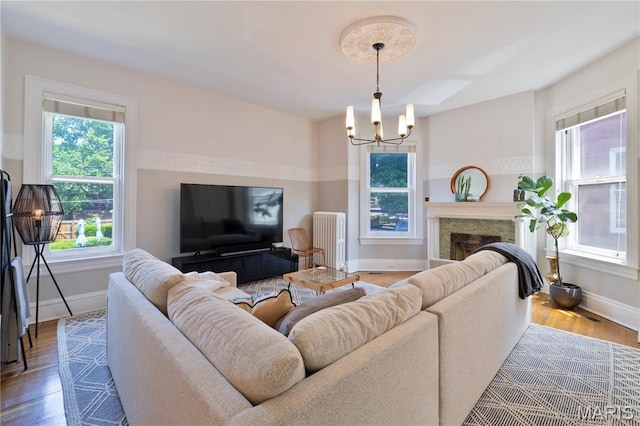 4365 Forest Park Ave, Saint Louis, MO 63108 - living room with radiator, wood finished floors, a chandelier, and a fireplace