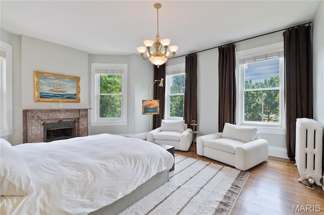 4365 Forest Park Ave, Saint Louis, MO 63108 - bedroom with radiator heating unit, a chandelier, wood finished floors, and a premium fireplace