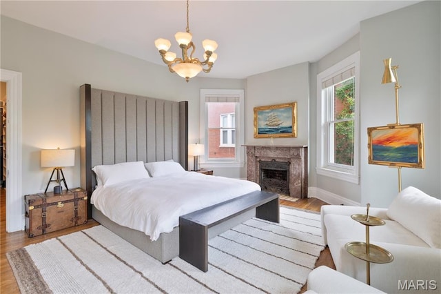 4365 Forest Park Ave, Saint Louis, MO 63108 - bedroom featuring wood finished floors, a chandelier, multiple windows, and a high end fireplace