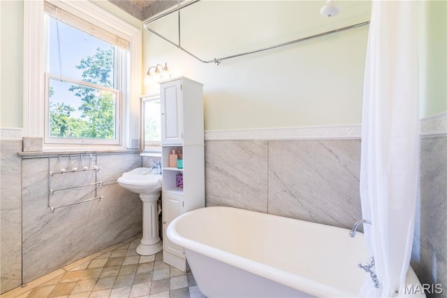 4365 Forest Park Ave, Saint Louis, MO 63108 - bathroom featuring tile walls, wainscoting, a freestanding tub, and tile patterned floors