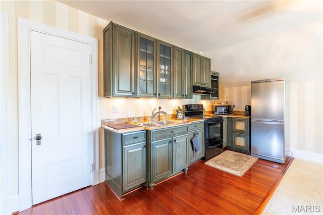 4365 Forest Park Ave, Saint Louis, MO 63108 - kitchen with black appliances, dark wood-style flooring, light countertops, glass insert cabinets, and wallpapered walls
