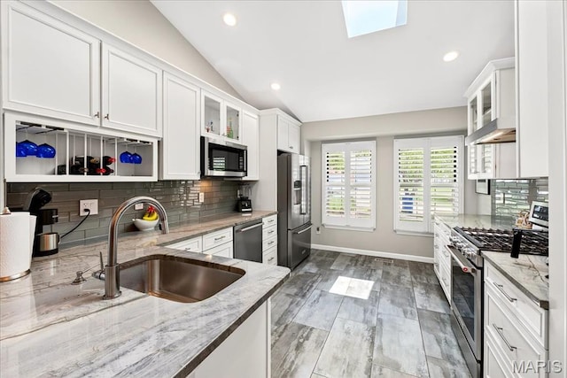 1909 King Arthur Ct, Saint Louis, MO 63146 - kitchen featuring appliances with stainless steel finishes, vaulted ceiling, white cabinetry, tasteful backsplash, and light stone counters