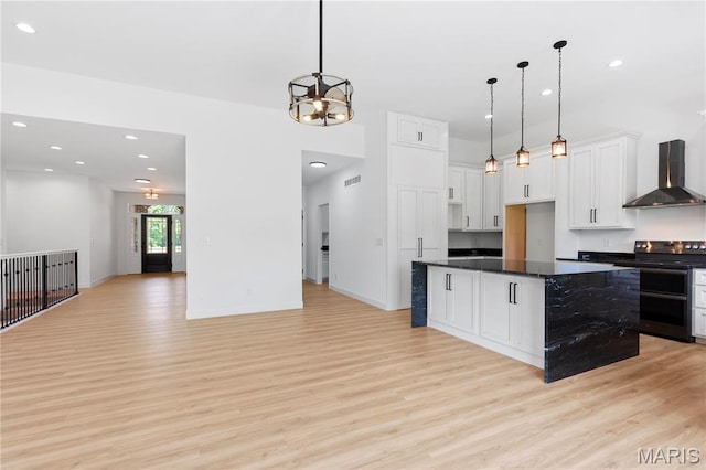 522 Dove Dr, Saint Charles, MO 63301 - kitchen featuring wall chimney exhaust hood, black range with electric cooktop, light wood-type flooring, white cabinetry, and hanging light fixtures