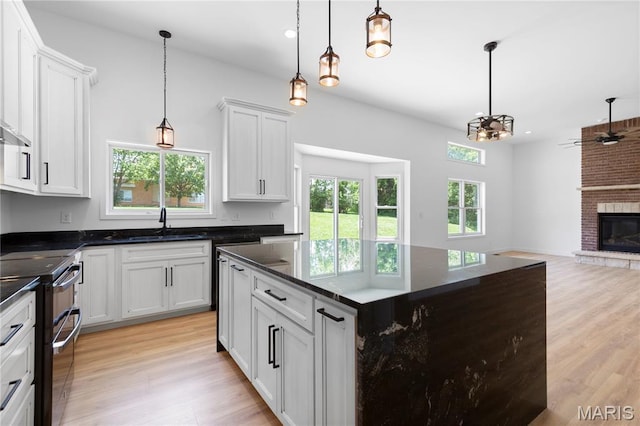 522 Dove Dr, Saint Charles, MO 63301 - kitchen with double oven range, light wood-style floors, open floor plan, a brick fireplace, and white cabinetry