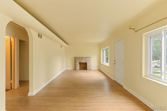 7637 Lynn Ave, University City, MO 63130 - unfurnished living room featuring plenty of natural light, arched walkways, a fireplace, and light wood finished floors