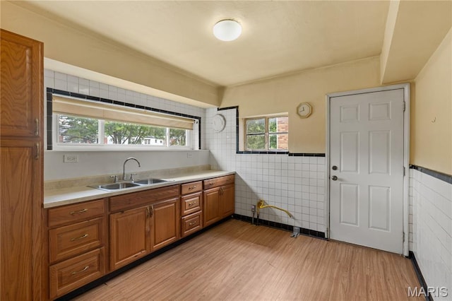 7637 Lynn Ave, University City, MO 63130 - kitchen featuring tile walls, brown cabinets, light wood-style floors, light countertops, and wainscoting