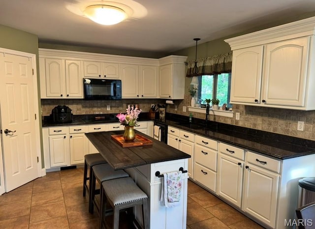 616 Remmick Stables Ct, Ofallon, MO 63368 - kitchen featuring black appliances, tasteful backsplash, dark tile patterned flooring, and a breakfast bar