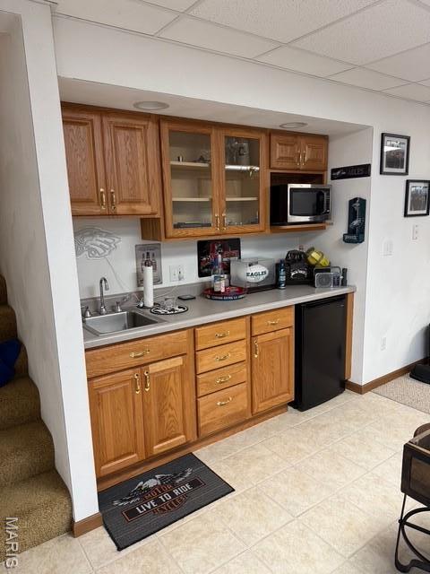 130 Regency Pl, Millstadt, IL 62260 - kitchen featuring stainless steel microwave, light countertops, brown cabinetry, glass insert cabinets, and a drop ceiling