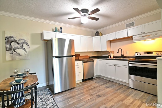 2745 Westphalia Ct Unit F, Oakville, MO 63129 - kitchen featuring appliances with stainless steel finishes, under cabinet range hood, crown molding, light wood-type flooring, and dark countertops