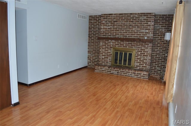 1726 Mayenne Ct, Saint Louis, MO 63125 - unfurnished living room with wood finished floors, a brick fireplace, and a textured ceiling