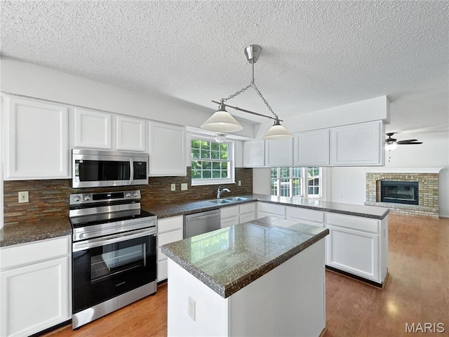 4033 Treeshadow Dr, Saint Peters, MO 63376 - kitchen featuring stainless steel appliances, a peninsula, white cabinetry, light wood-style floors, and a textured ceiling
