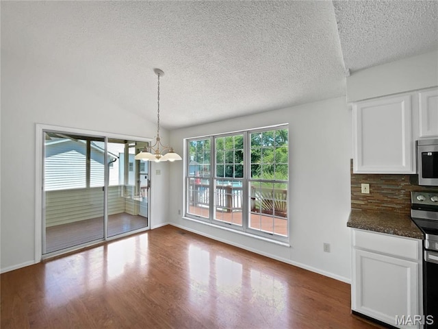 4033 Treeshadow Dr, Saint Peters, MO 63376 - unfurnished dining area featuring a textured ceiling, dark wood-type flooring, a chandelier, and vaulted ceiling
