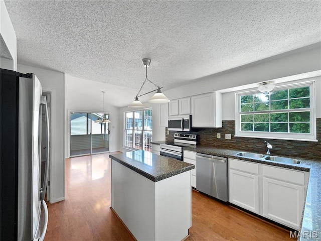 4033 Treeshadow Dr, Saint Peters, MO 63376 - kitchen featuring appliances with stainless steel finishes, backsplash, a center island, plenty of natural light, and a textured ceiling