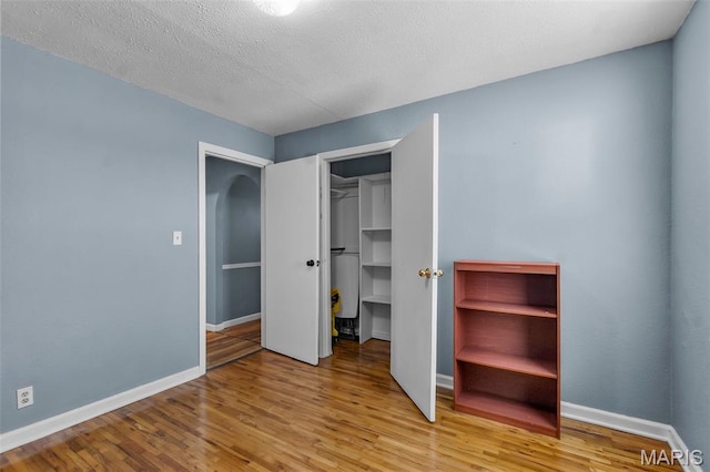 5748 State Highway 25, Cape Girardeau, MO 63701 - unfurnished bedroom featuring wood finished floors, a textured ceiling, a closet, and a spacious closet