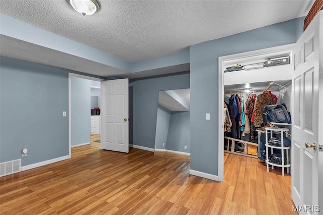 5748 State Highway 25, Cape Girardeau, MO 63701 - unfurnished bedroom featuring a walk in closet, a closet, light wood finished floors, and a textured ceiling