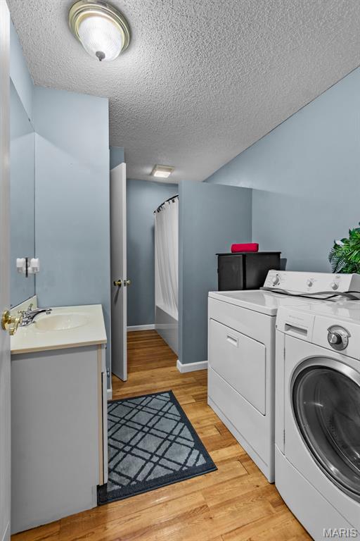 5748 State Highway 25, Cape Girardeau, MO 63701 - laundry room featuring washer and dryer, a textured ceiling, and light wood finished floors