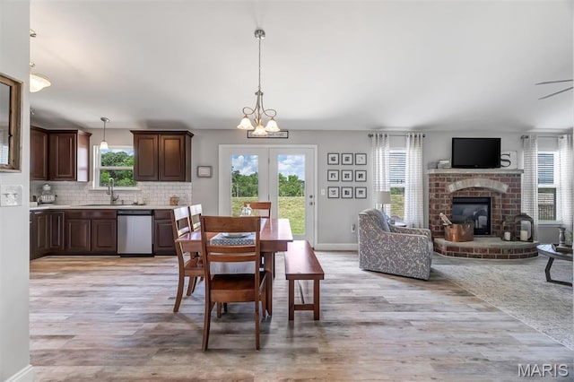 1209 Riesling Ln, Pevely, MO 63070 - dining area with light wood-style floors, a brick fireplace, a chandelier, and a ceiling fan
