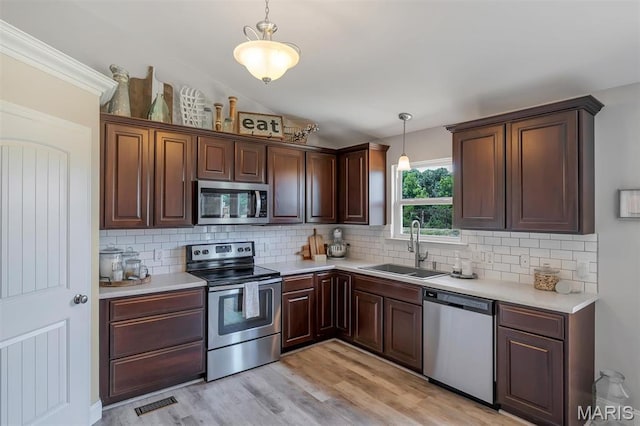 1209 Riesling Ln, Pevely, MO 63070 - kitchen featuring stainless steel appliances, light countertops, decorative backsplash, light wood-type flooring, and vaulted ceiling